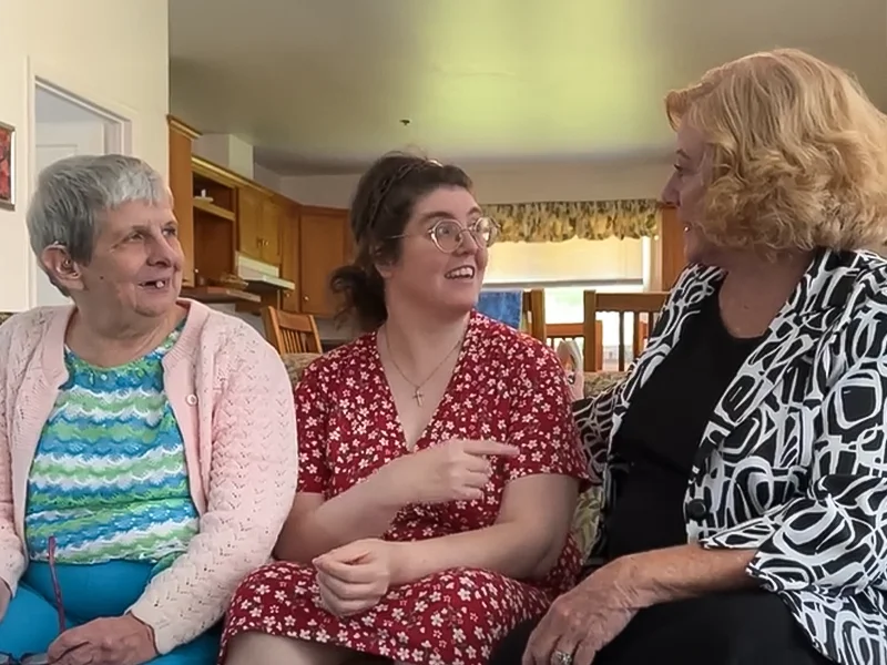 Three women are sitting on a couch, discussing independent living.